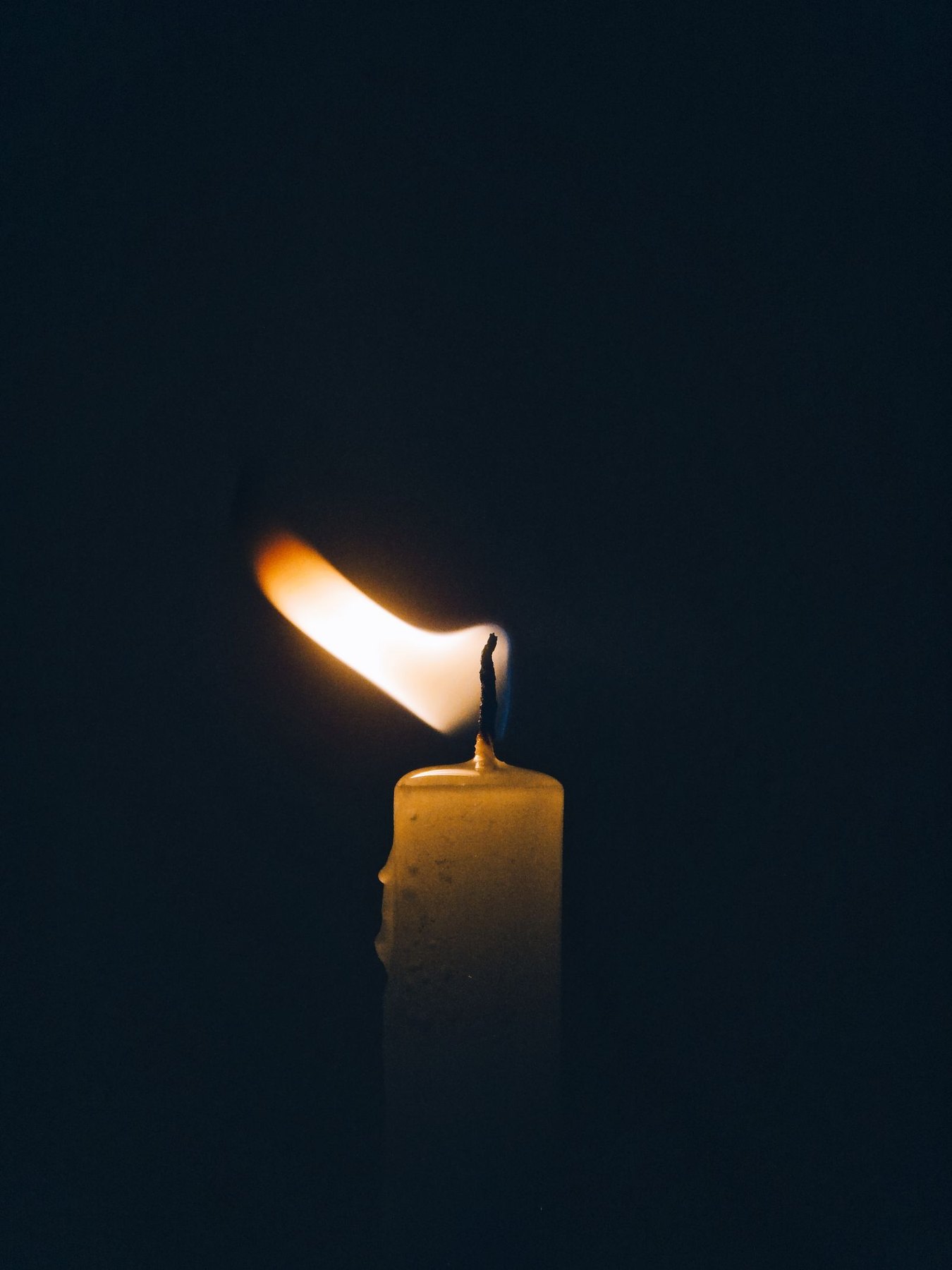 Una vela real encendida en la oscuridad